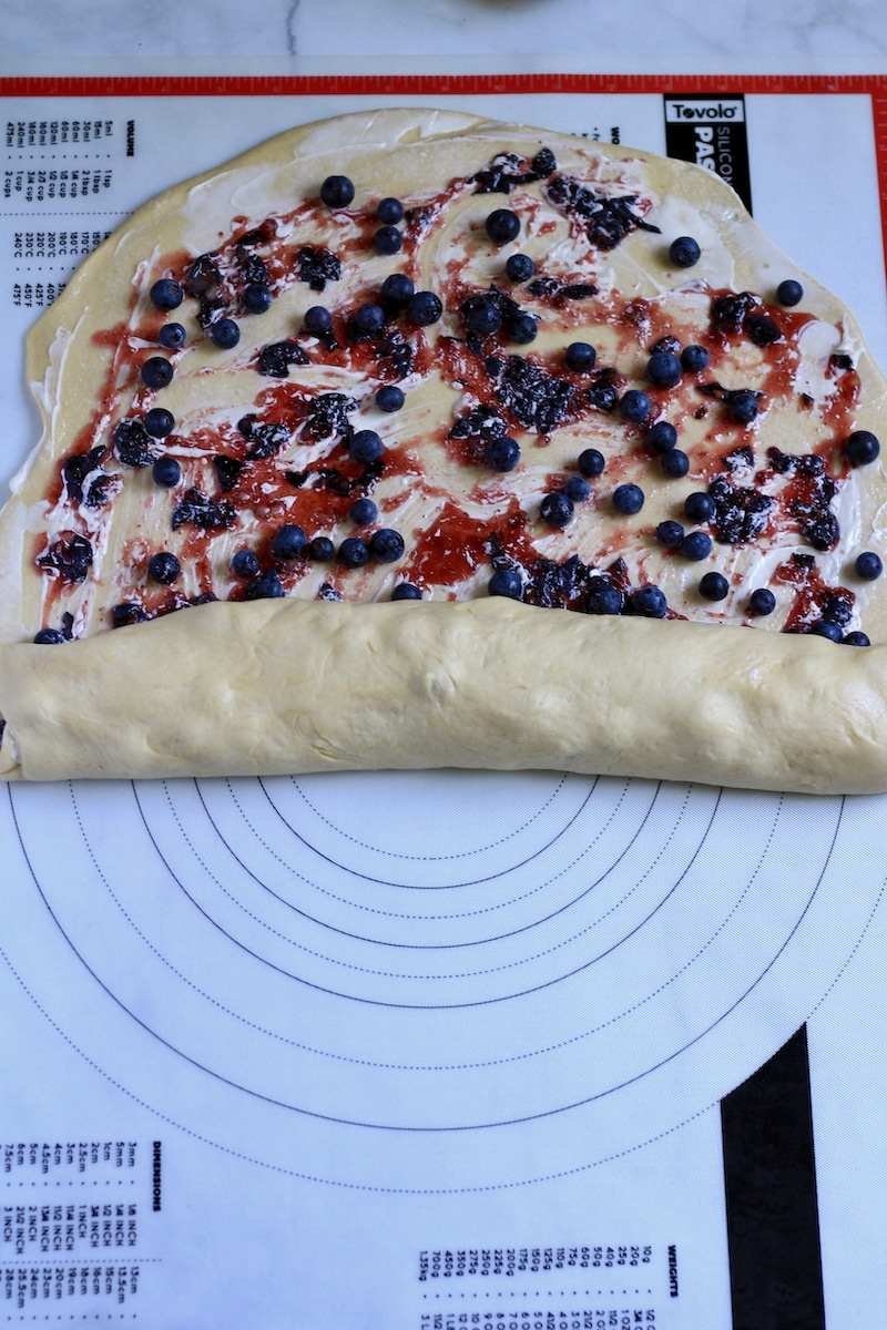Lemon Blueberry Sweet Roll dough being rolled up the short side before being cut.