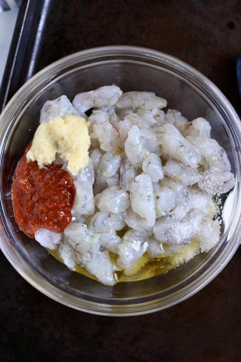 A glass bowl with the chili garlic shrimp ingredients before stirring together.