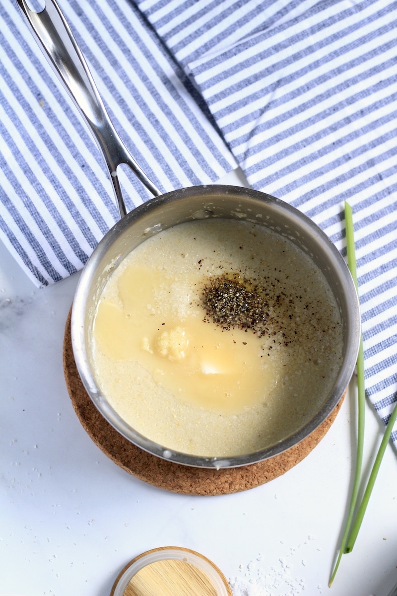 A saucepan with garlic butter grits before mixing the garlic butter and spices in.