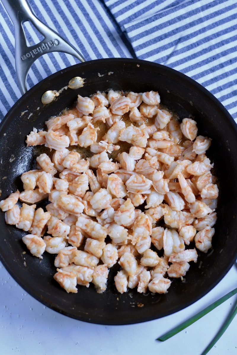 A large black skillet with chili garlic shrimp after cooking.