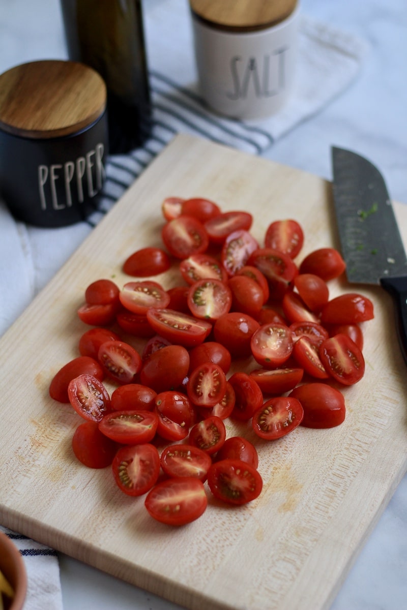 Grape tomatoes sliced in half on a cutting board.