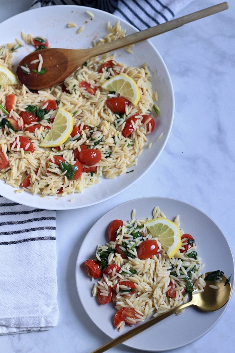 A white bowl in the top left with lemon orzo pasta salad and a plate in the bottom right with lemon orzo pasta salad.