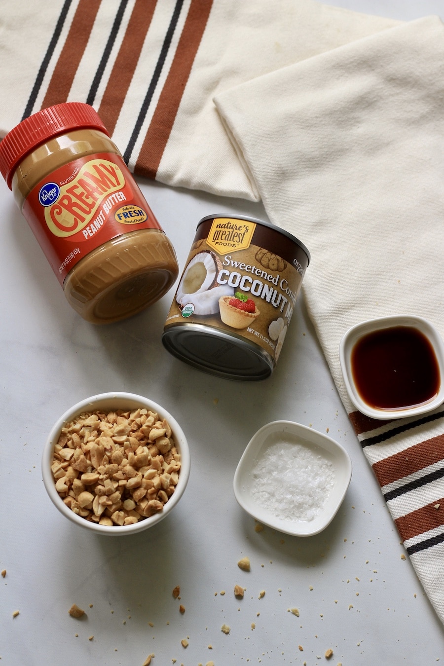 Ingredients for peanut butter fudge on a counter with an orange and brown striped towel.