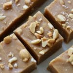 A close up of a square of peanut butter fudge topped with fresh chopped peanuts.