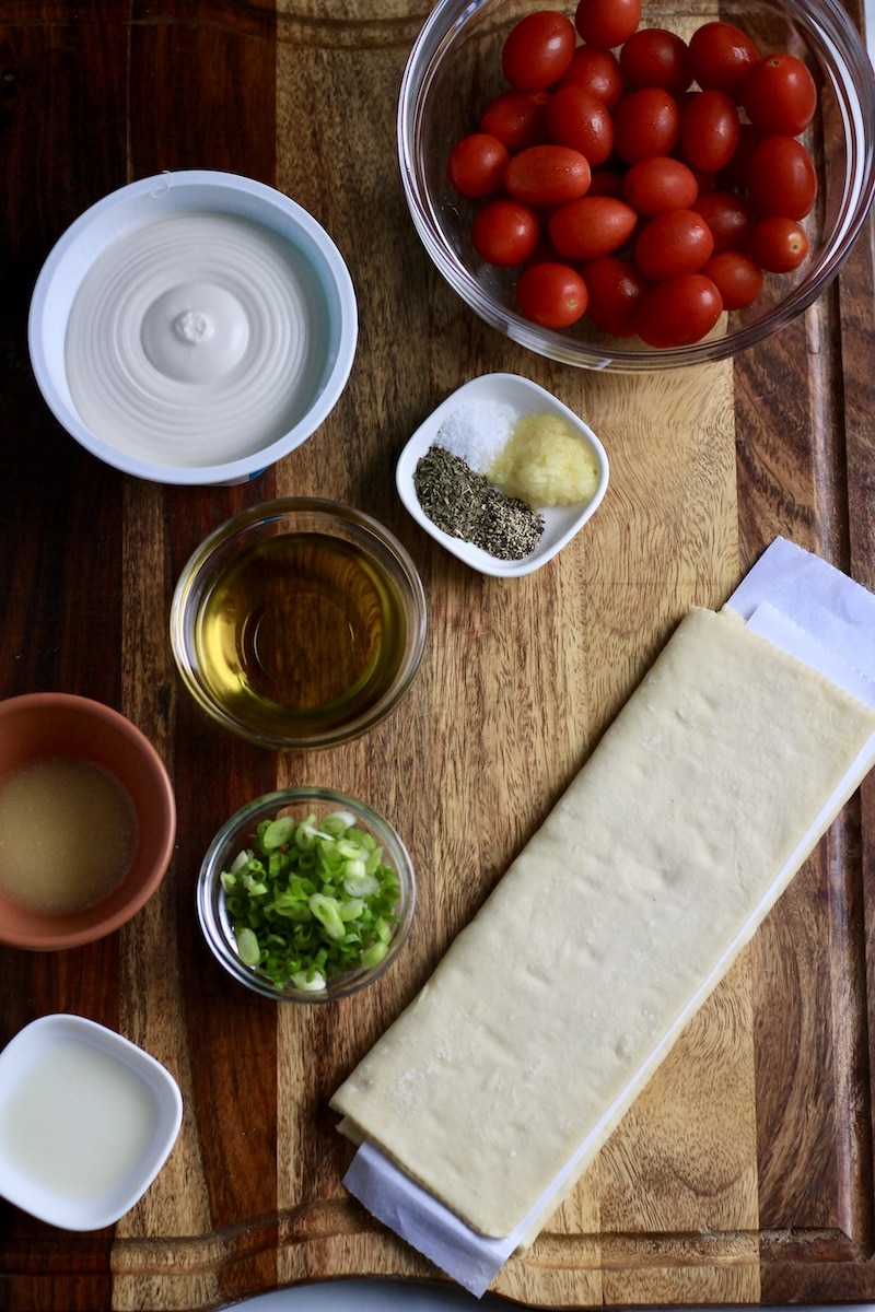 Ingredients for roasted tomato tart on a wooden cutting board.