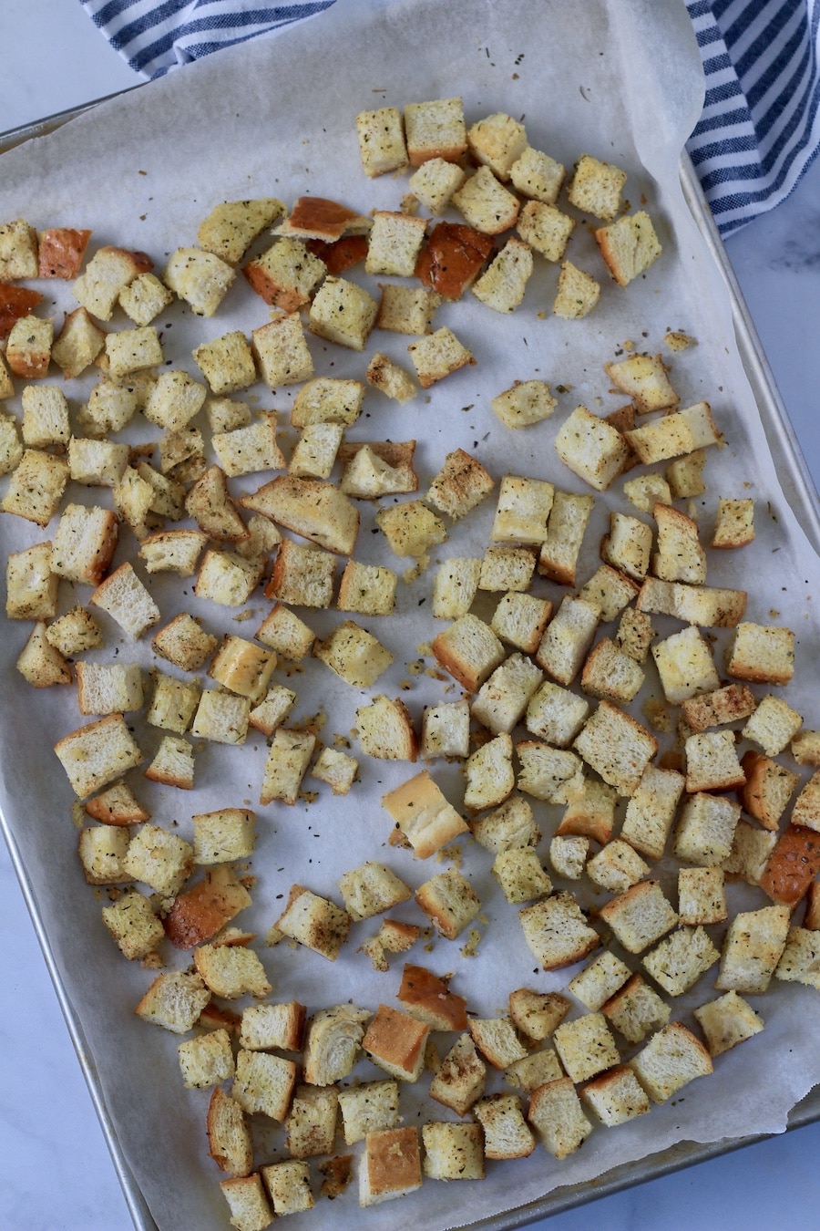 A parchment paper lined baking sheet with homemade croutons after baking.