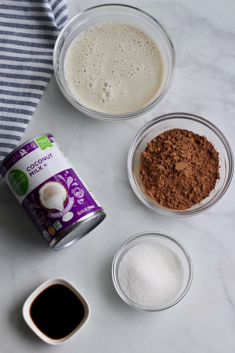 Ingredients for vegan fudgesicles on a counter in glass bowls.