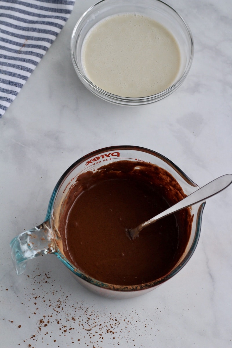 A liquid measuring cup with all of the ingredients except oat milk mixed in with a silver fork.
