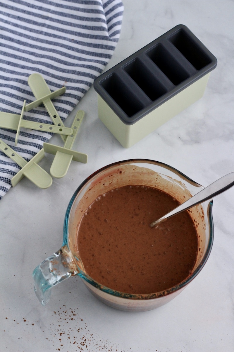 A liquid measuring cup with the vegan fudgesicle liquid and a mini popsicle mold in the back.