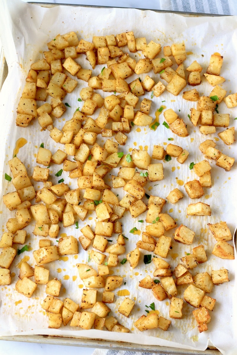 A parchment paper lined baking sheet with roasted breakfast potatoes.
