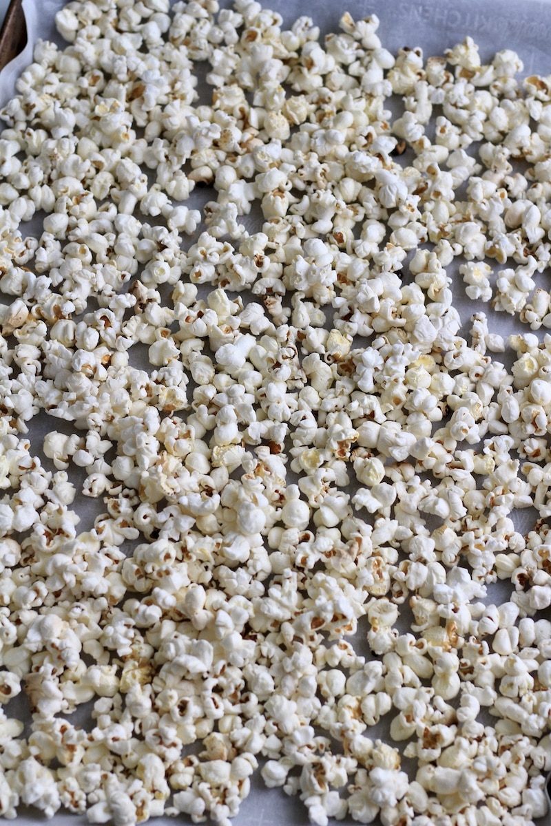 A parchment paper lined baking sheet with fresh popcorn.