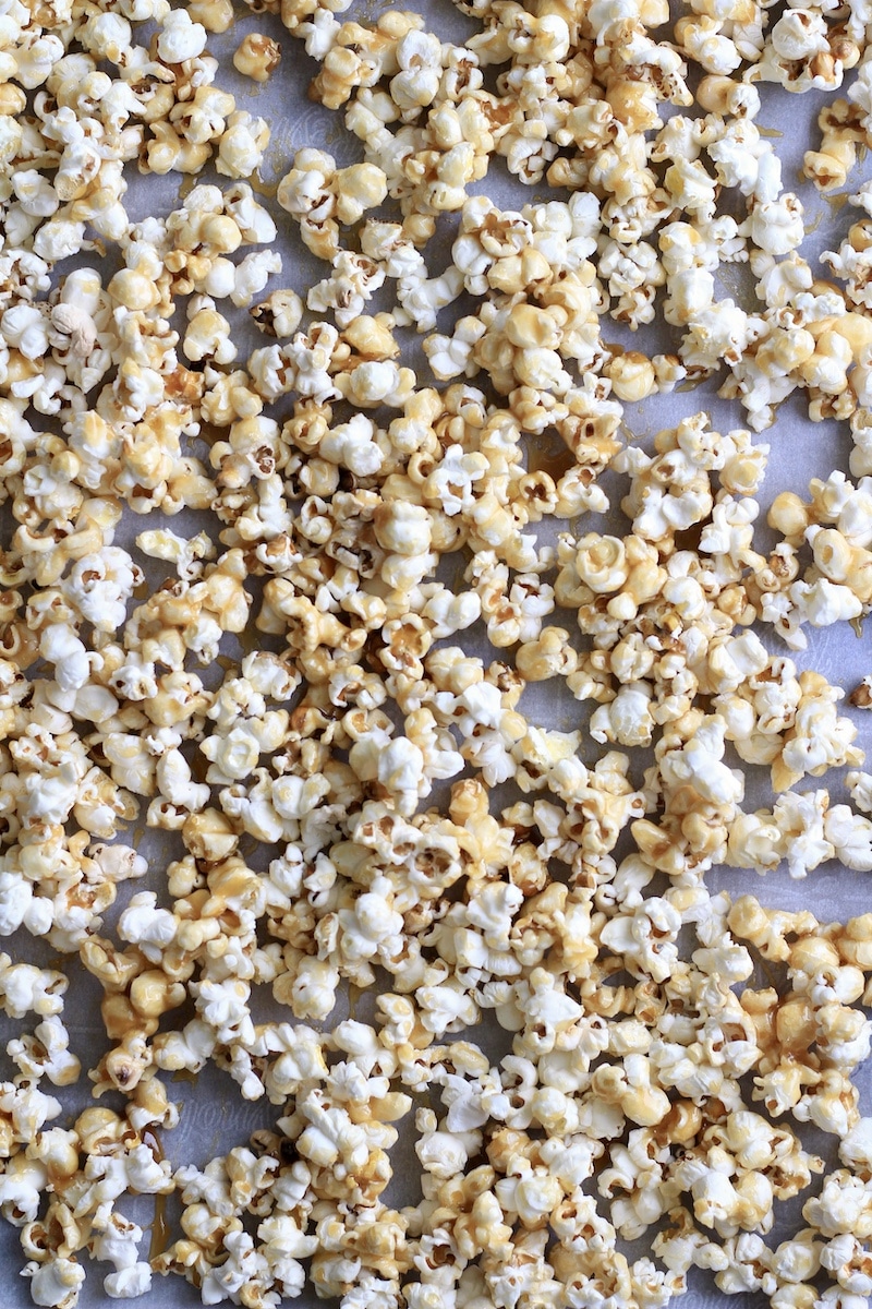 Caramel corn on a parchment paper lined baking sheet after first round of baking.