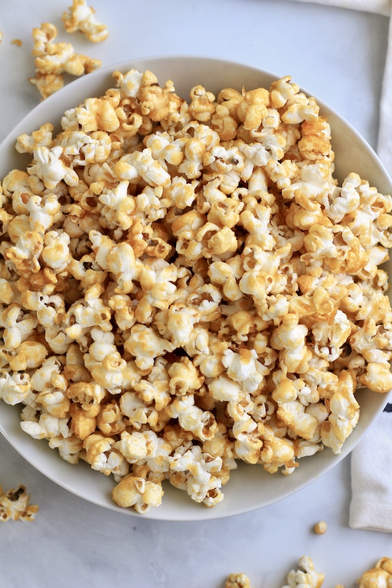 A white bowl with vegan caramel corn on a white counter.