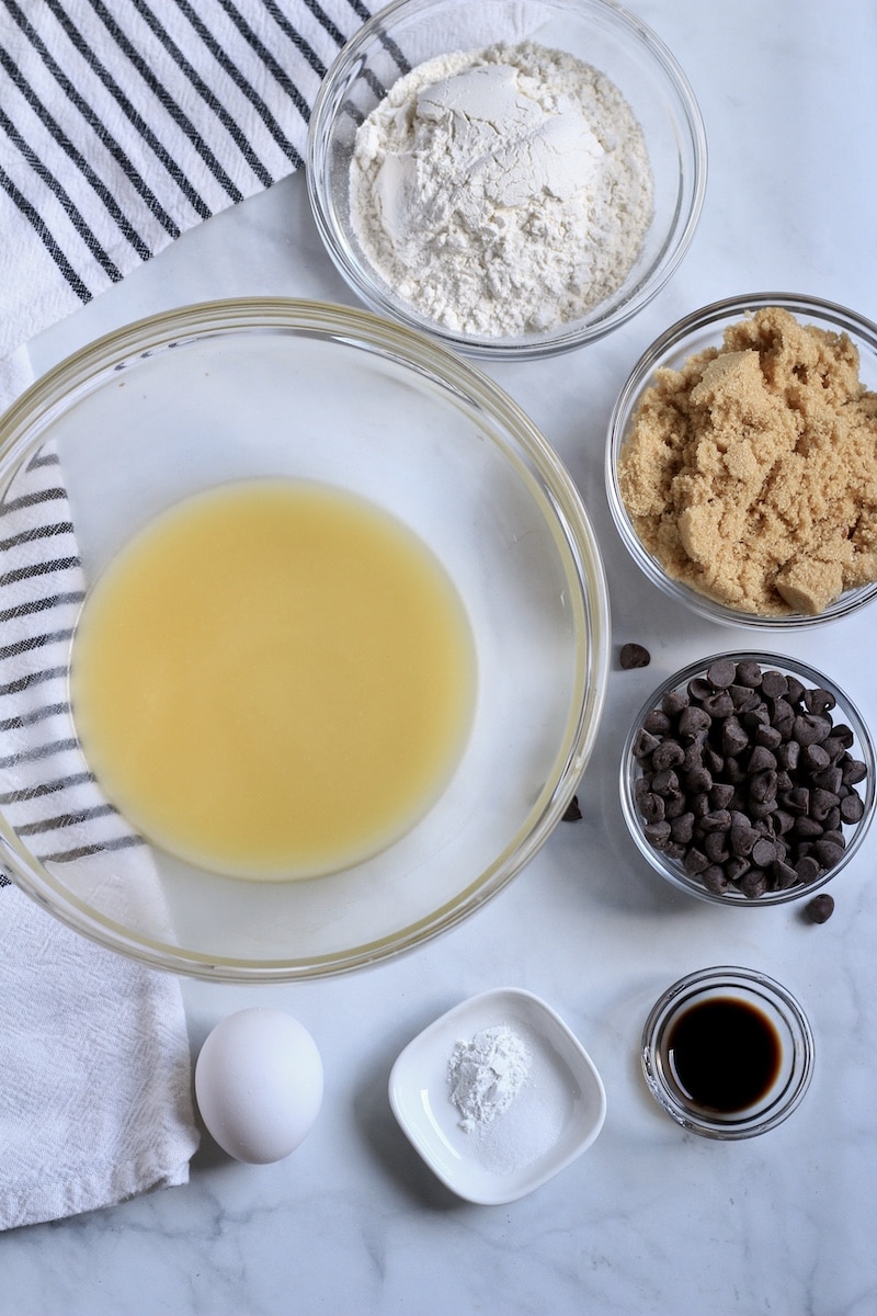 Melted plant-based butter in a medium bowl on the left with the remaining ingredients for blondies on the right.