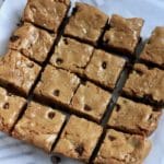 A square photo of chocolate chip blondies on parchment paper.