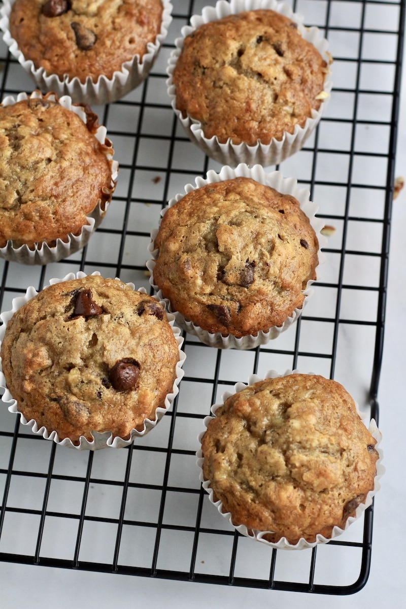 A black wire cooling rack with chunky monkey muffins after baking.