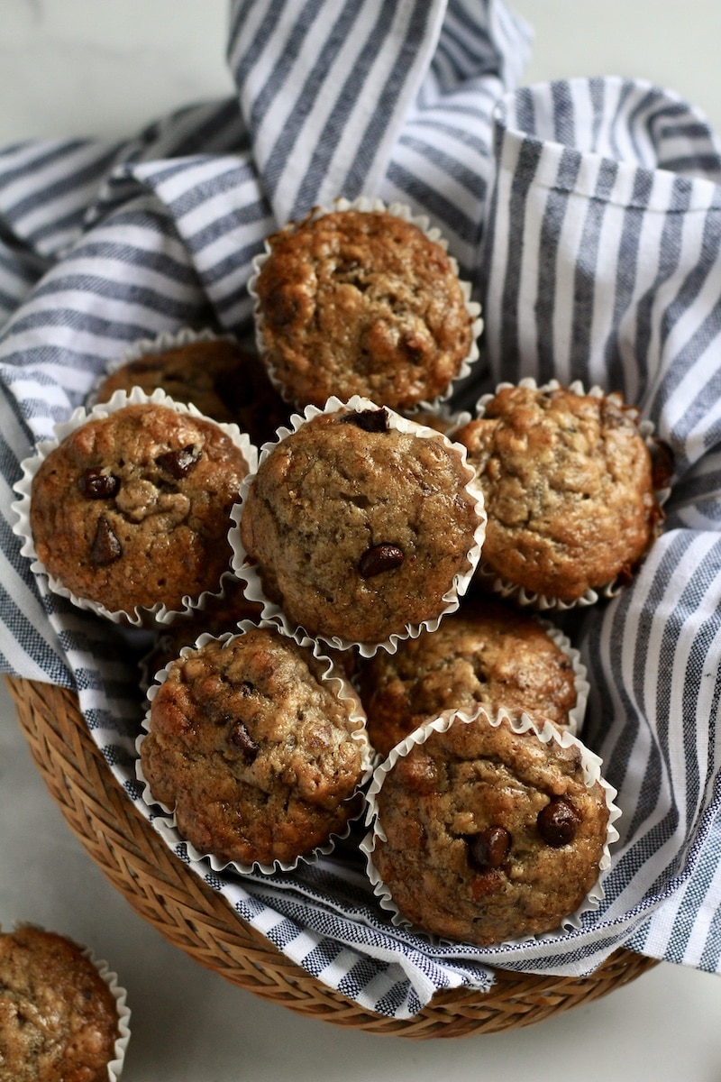A top down photo of chunky monkey muffins in basket with blue and white striped towel.