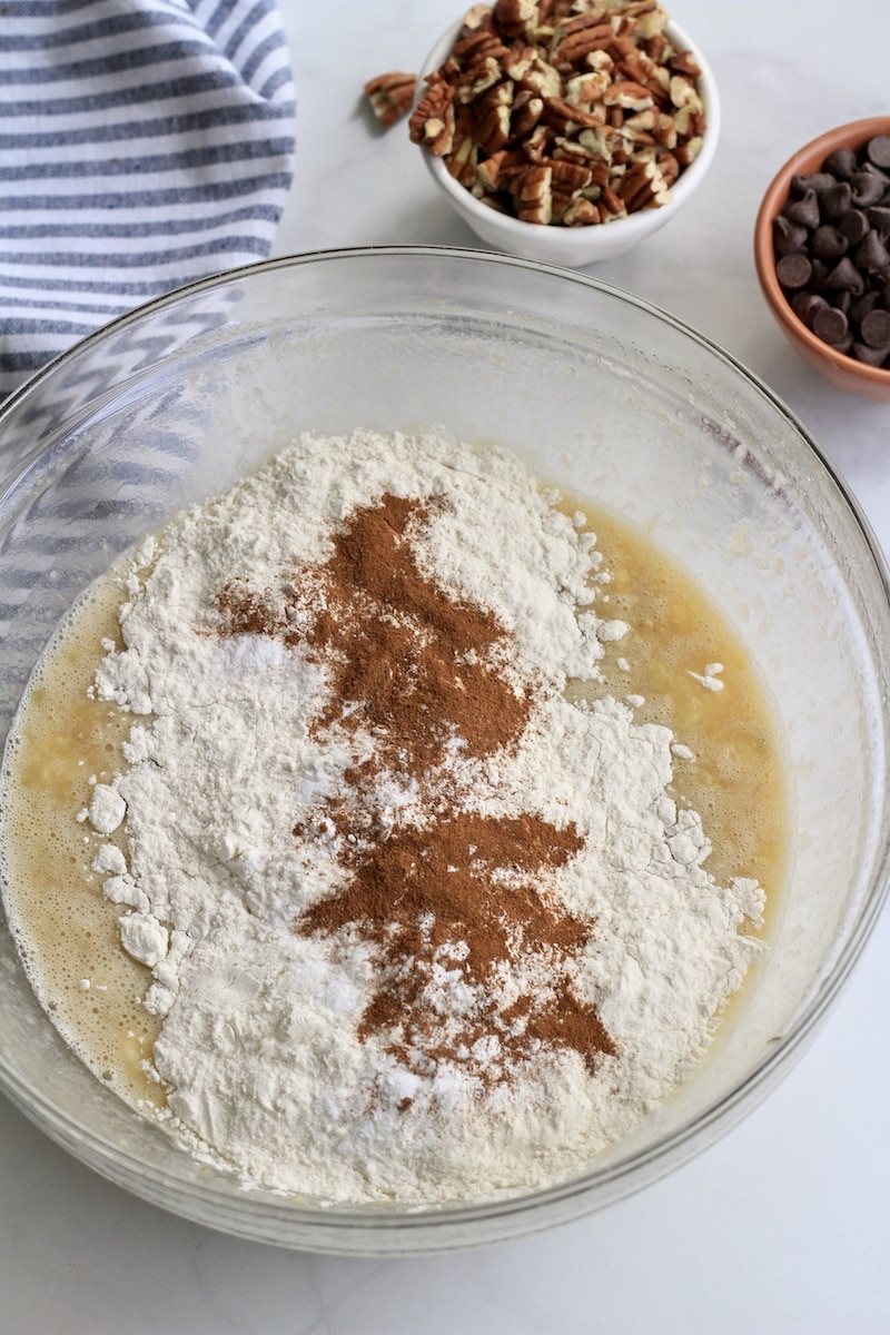 A large glass bowl with the dry ingredients on top of the wet ingredients before folding together.