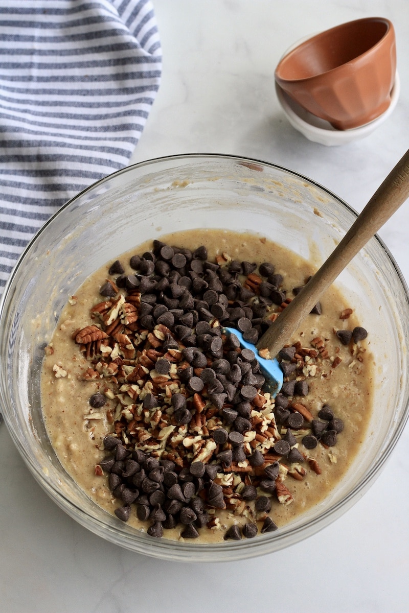 A large glass bowl with banana muffins topped with chocolate and pecans.