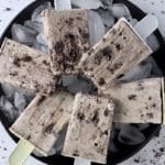 A square photo of cookies and cream popsicles on a plate with ice.