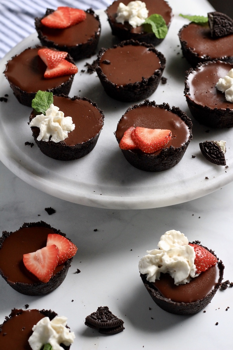 A raised plate of no bake chocolate tarts with mini chocolate tarts below.