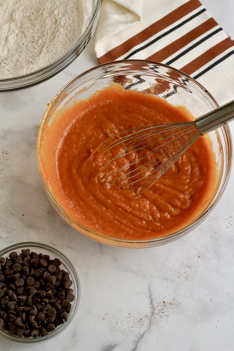 A glass bowl with a whisk after mixing the wet ingredients together.