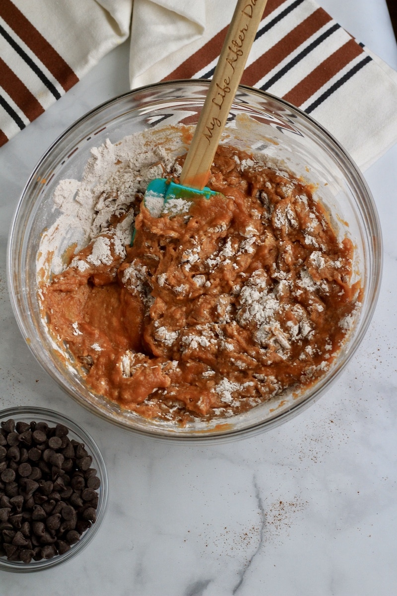 A glass bowl with the wet ingredients being folded into the dry ingredients.