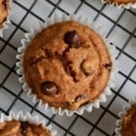 A square top down photo of a pumpkin muffin with chocolate chips on a cooling rack.