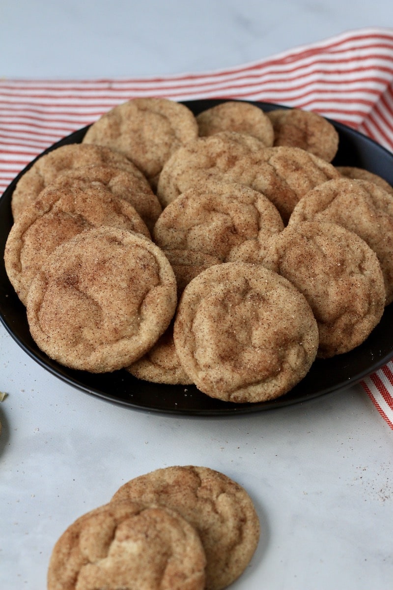 A plate of vegan snickerdoodle cookies with a red and white striped towel.