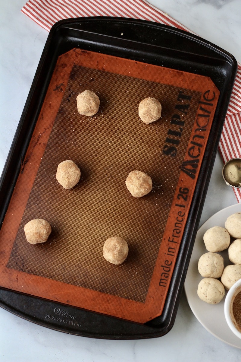 A rimmed baking sheet with a silpat topped with unbaked snickerdoodle cookie dough.