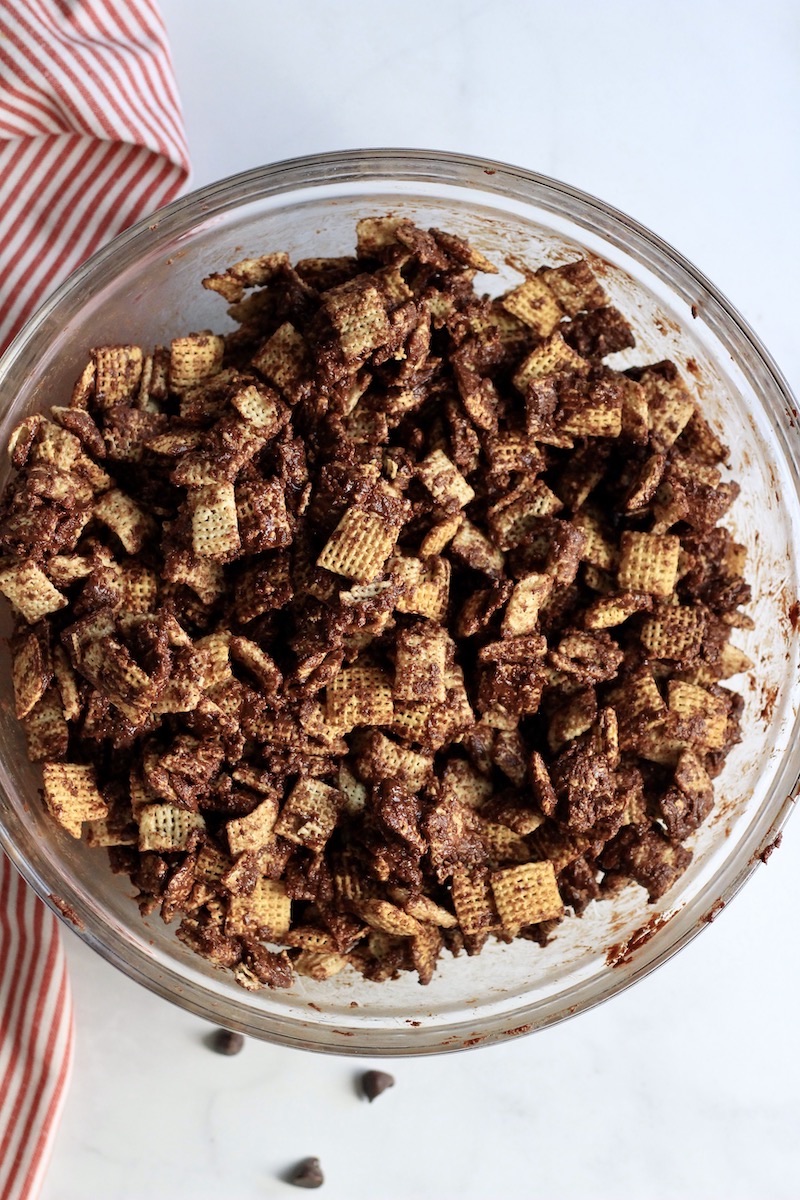 A large glass bowl with the chocolate cookie butter mixture coating the Chex.