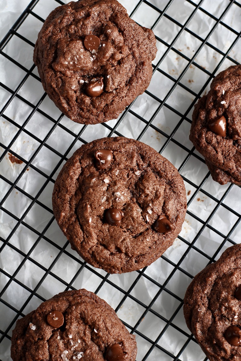 A drying rack with chocolate chocolate chip cookies cooling.