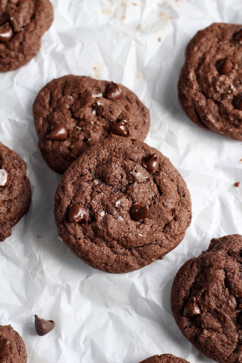 Two double chocolate chip cookies in the middle of a parchment paper.