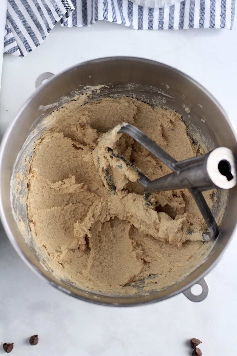 A mixing bowl with a paddle attachment with creamed butter and sugar.