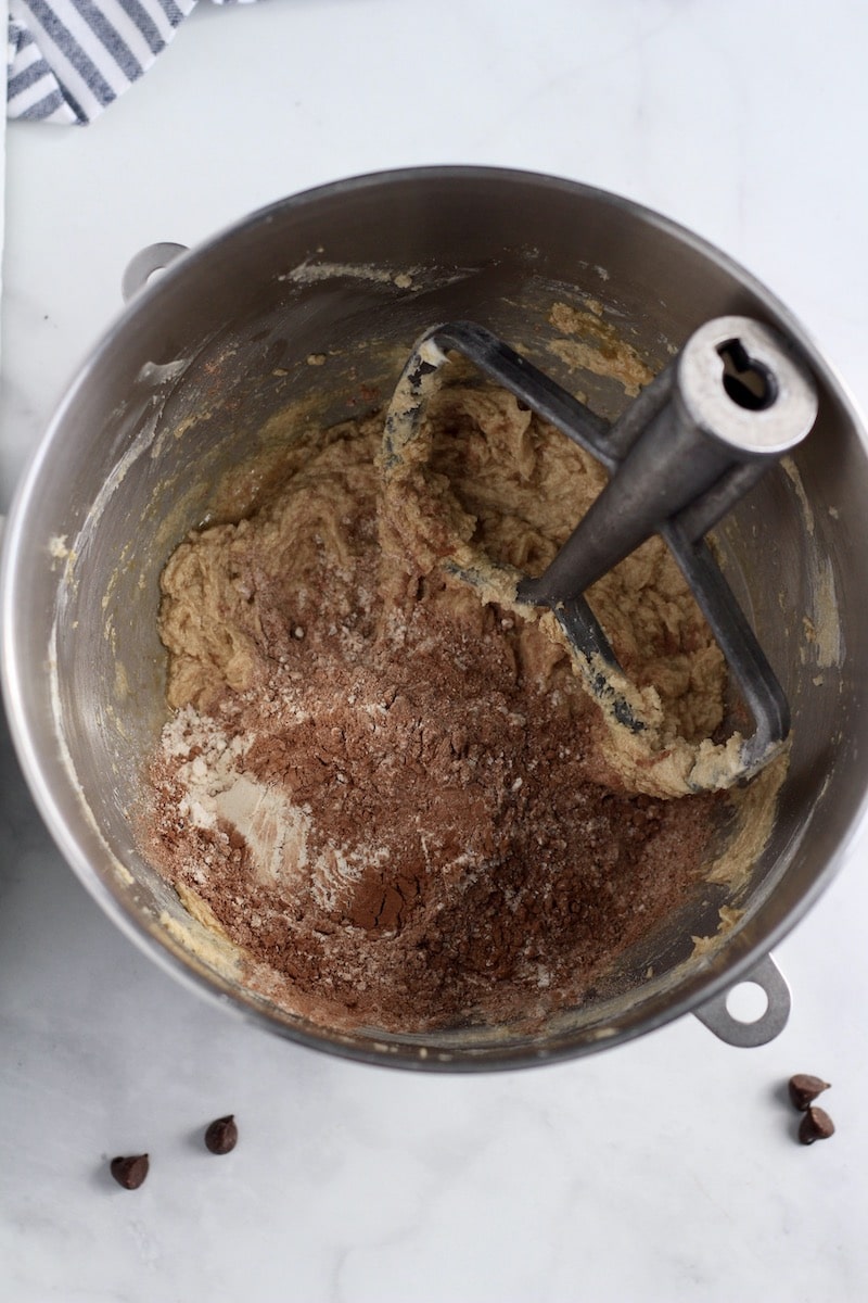 A mixing bowl with a paddle attachment with the dry ingredients added.