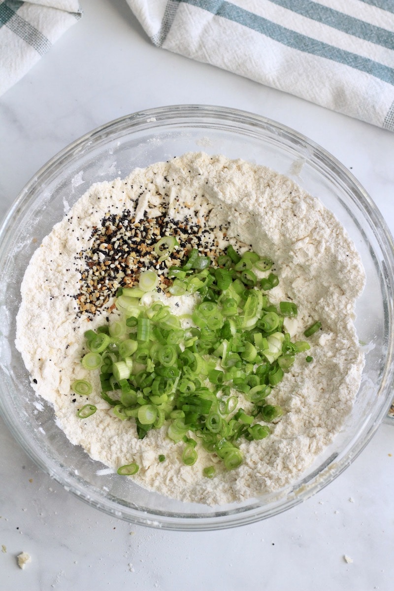 Crumbly flour mixture in a glass bowl topped with scallions and everything bagel seasoning.