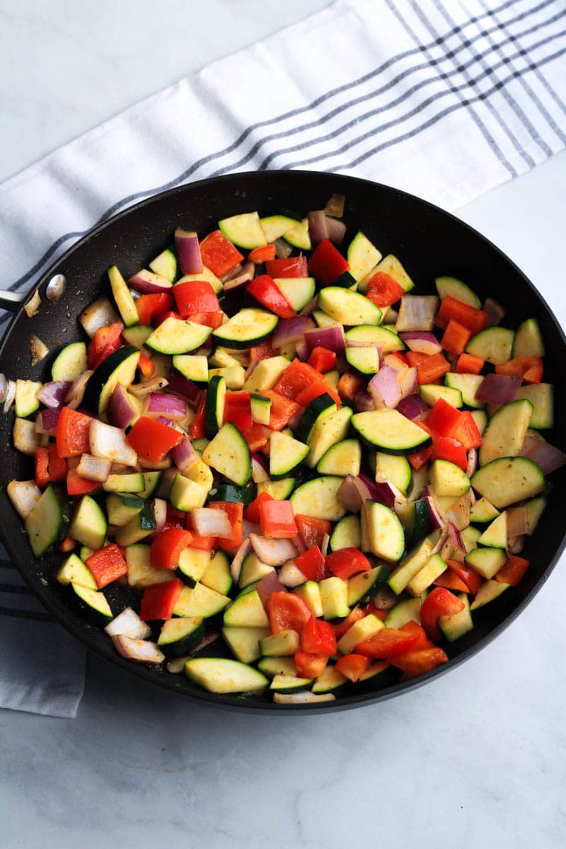 A black skillet with vegetables after cooking.