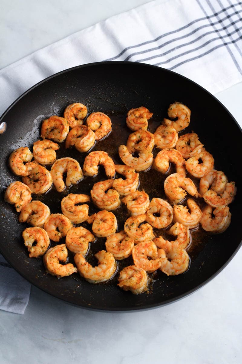 A black skillet with shrimp after cooking.