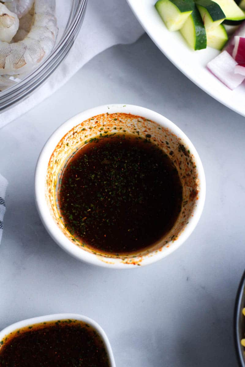 A white bowl with the shrimp marinade all mixed together.