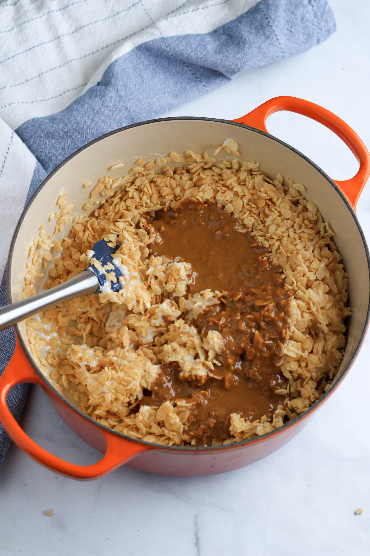 Rice krispie cereal topped with melted cookie butter in an orange pot.