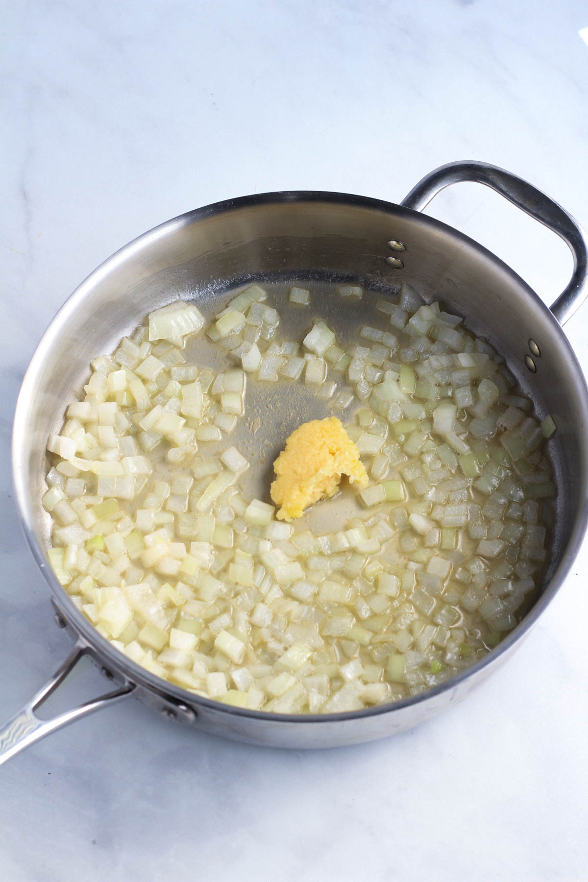 A skillet with onion, plant butter, and garlic cooking.