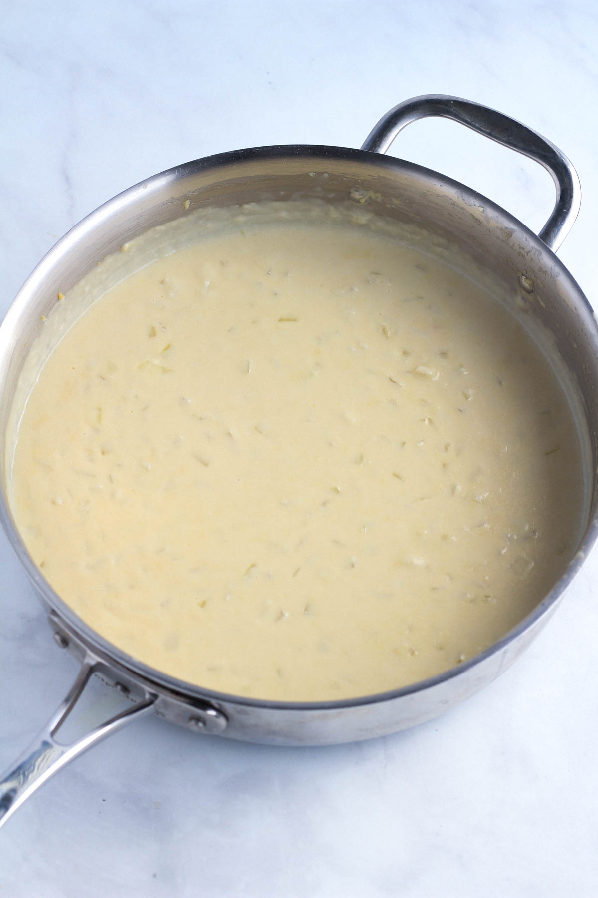 A stainless steel skillet with garlic cream sauce thickening.