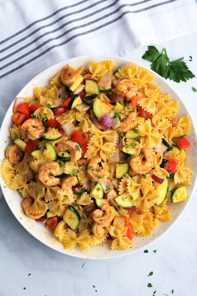 A top down photo of a shrimp and vegetable pasta skillet in a large white bowl.