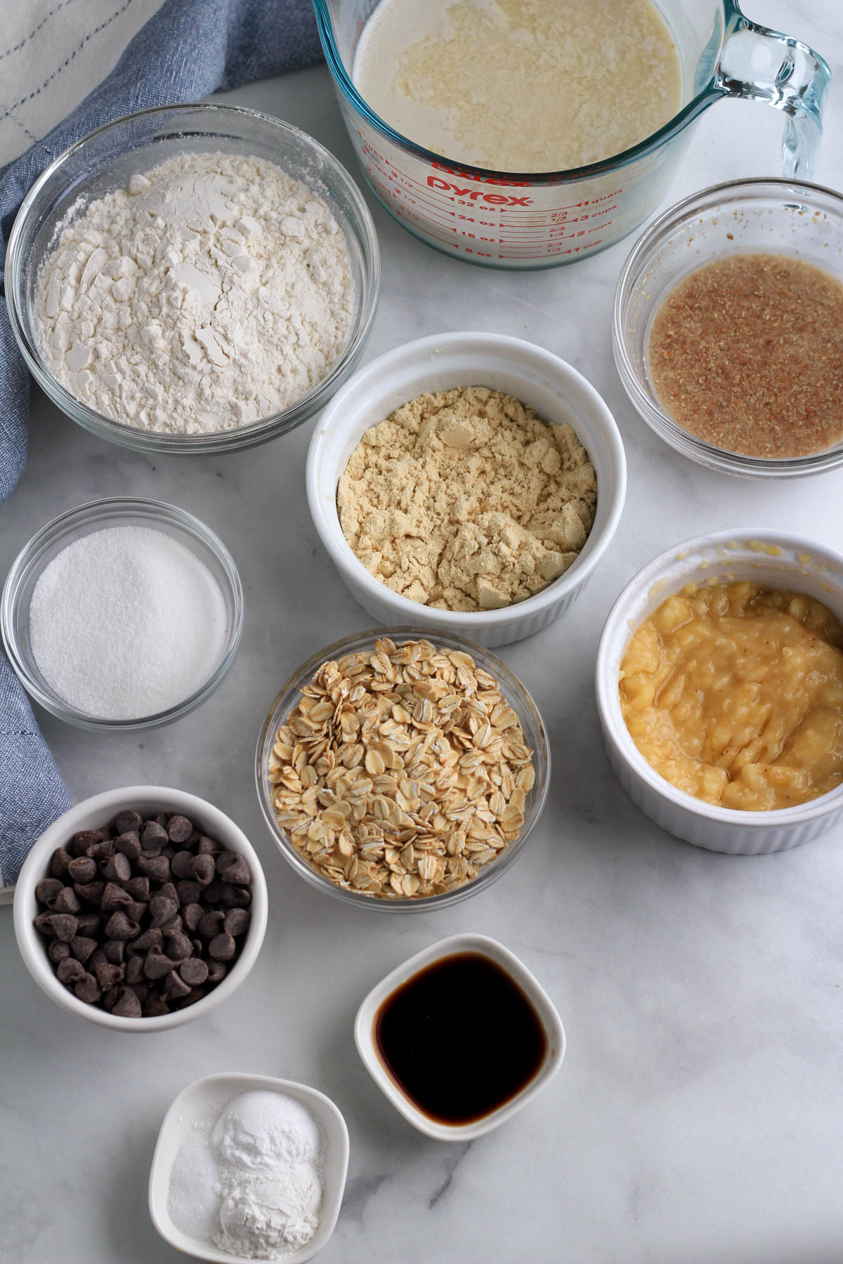 Ingredients for vegan chocolate chip pancakes on a white counter in bowls.