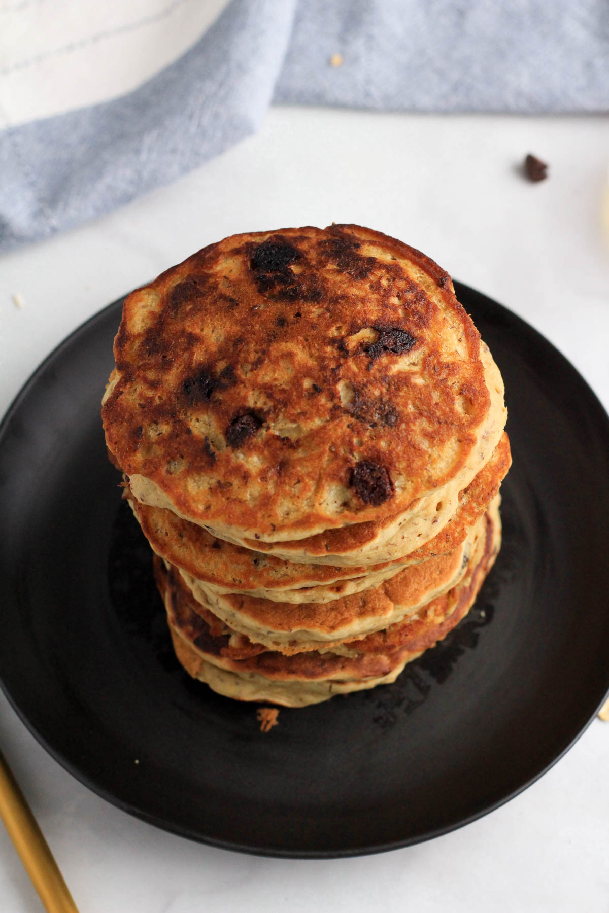 A plain stack of vanilla chocolate chip pancakes on a black plate.