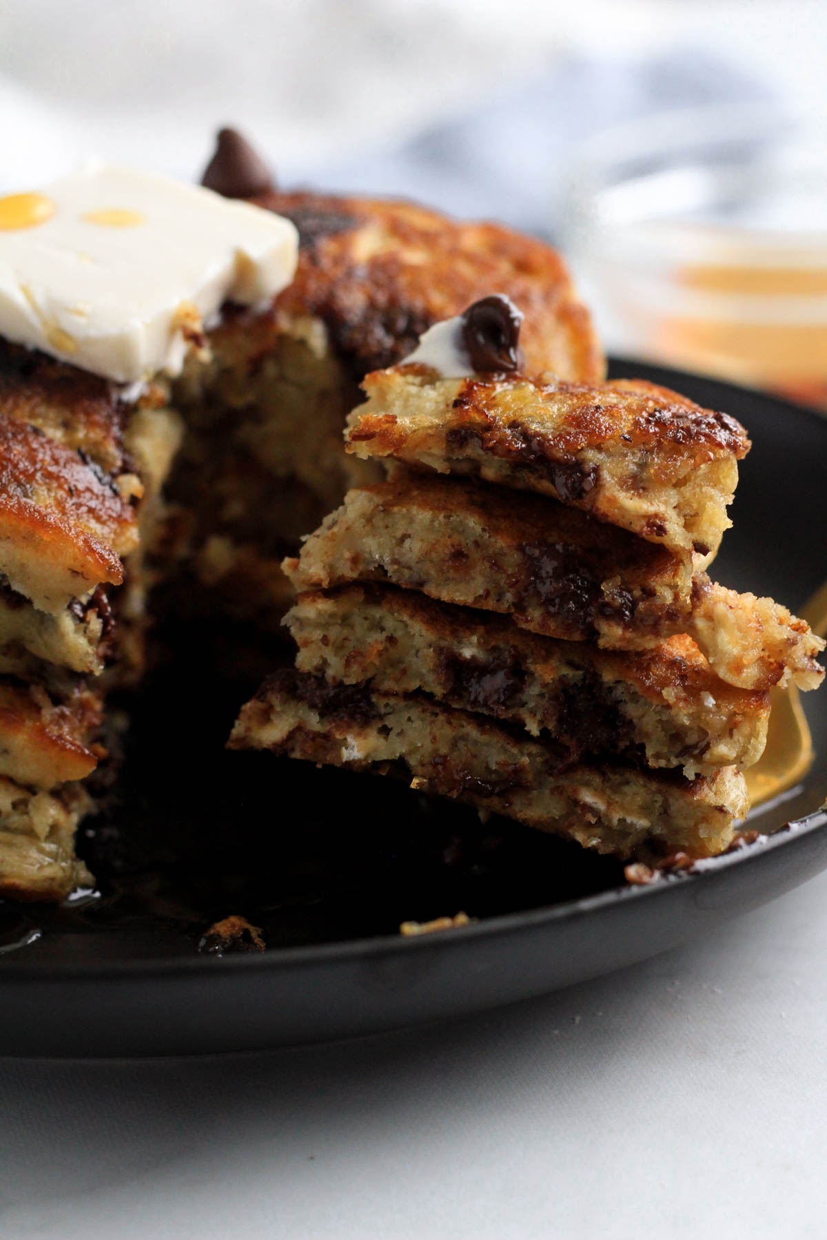 A triangle bite of vanilla chocolate chip vegan pancakes on a black plate.