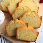 A square photo of sliced vanilla pound cake on a wooden cutting board.