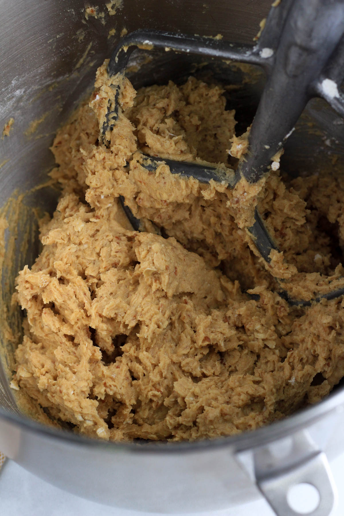 A close up of the peanut butter oatmeal cookie dough in the mixing bowl with a silver paddle attachment.