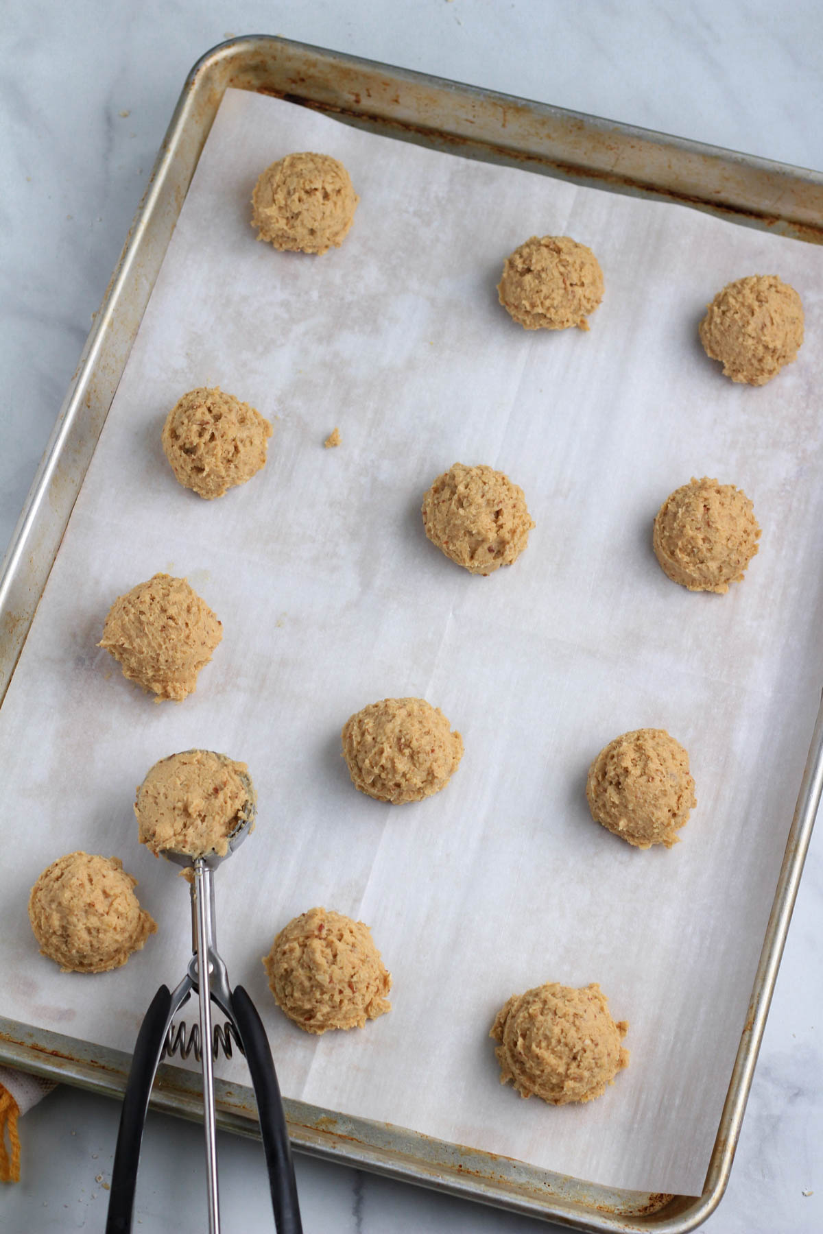 A parchment paper lined baking sheet with dough balls of vegan peanut butter cookie dough.