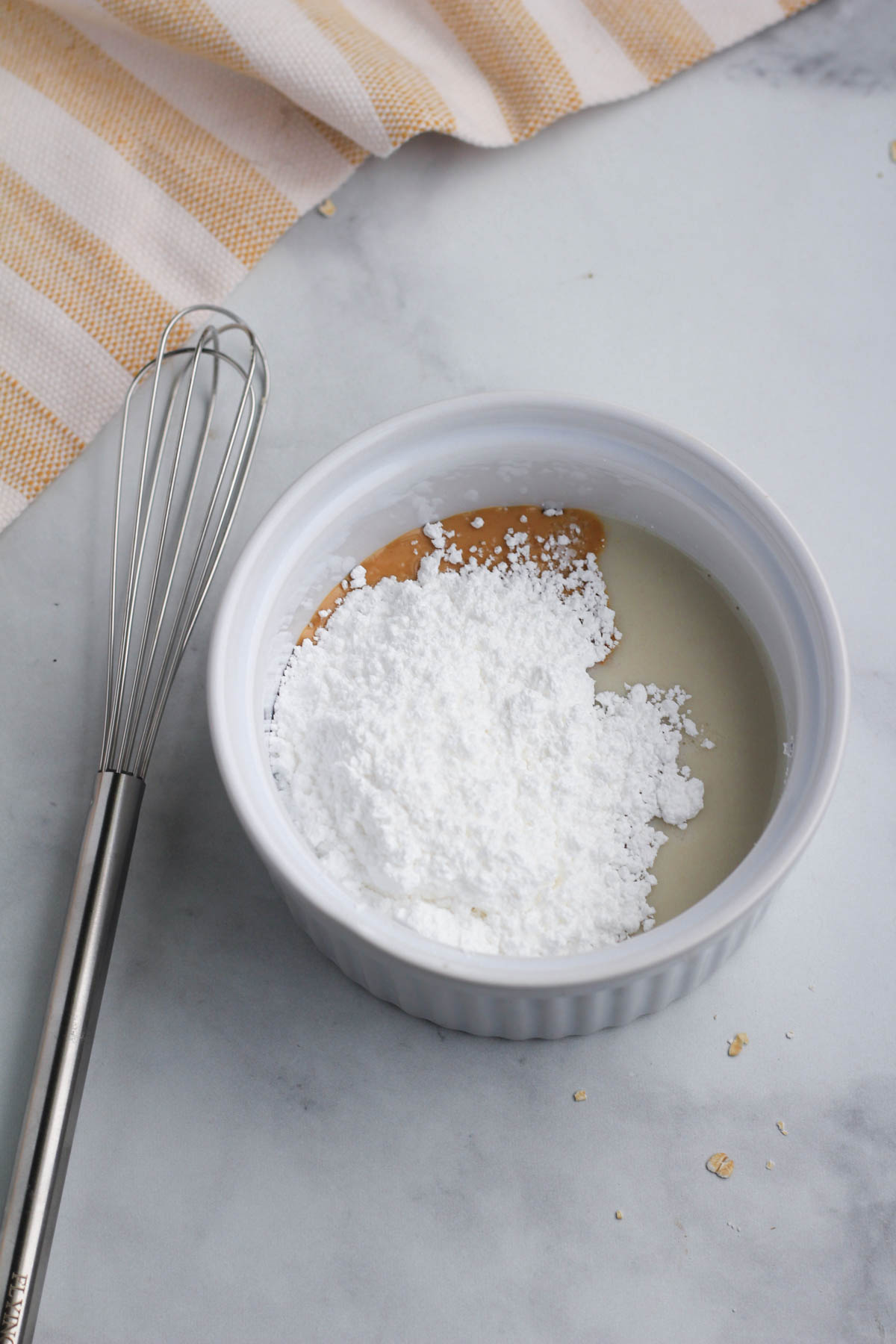 A white ramekin with the ingredients for the frosting before mixing.